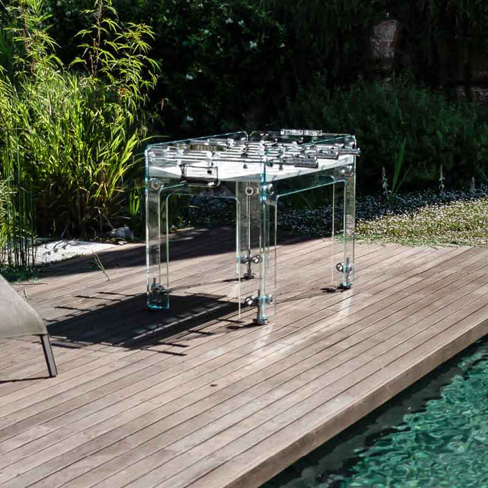 Teckell Fuoriclasse Foosball Table on a wooden deck with greenery, emphasizing its blend with natural surroundings.