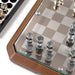 A detailed close-up of the Teckell Stratego game board, focusing on the intricate design of the chess pieces and the quality of the low iron tempered glass top set in a Canaletto walnut wood base.