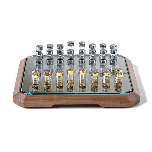 A front view of the Teckell Stratego game board, showcasing its luxurious Canaletto walnut wood base and intricately designed chess pieces made from extra-clear borosilicate glass adorned with 24K gold and chrome-plated brass.