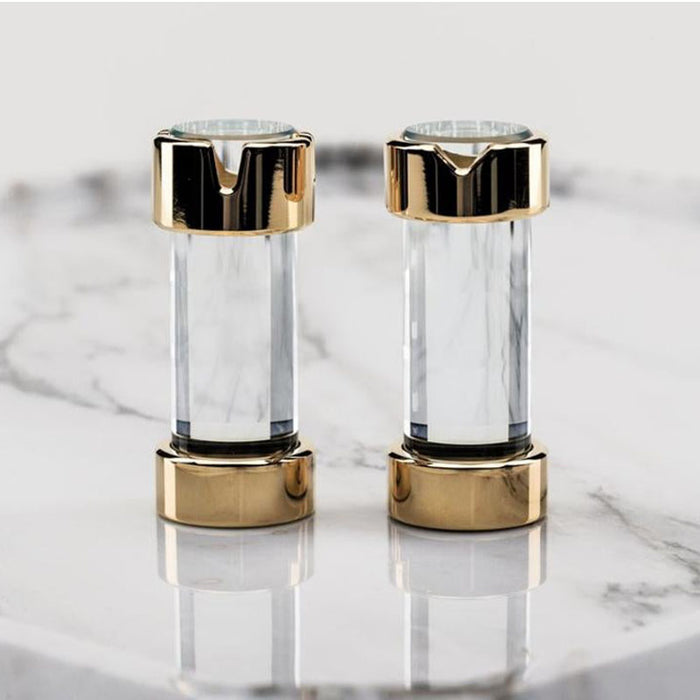 A pair of chess pieces crafted from extra-clear borosilicate glass and adorned with 24K gold, placed on a marble surface.