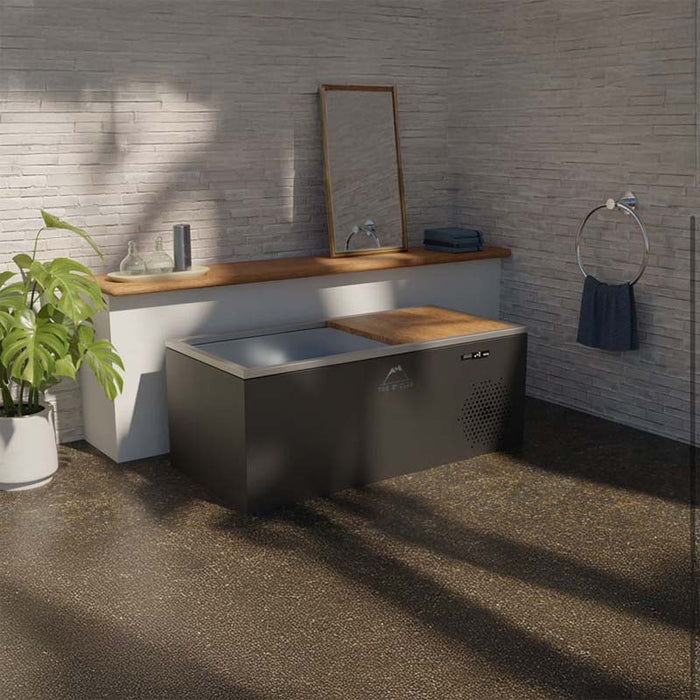 Elegant side view of the Three Degree Club Yukon Ice Bath in a contemporary bathroom setting, featuring a robust build with a solid wood footrest for comfort during cold therapy