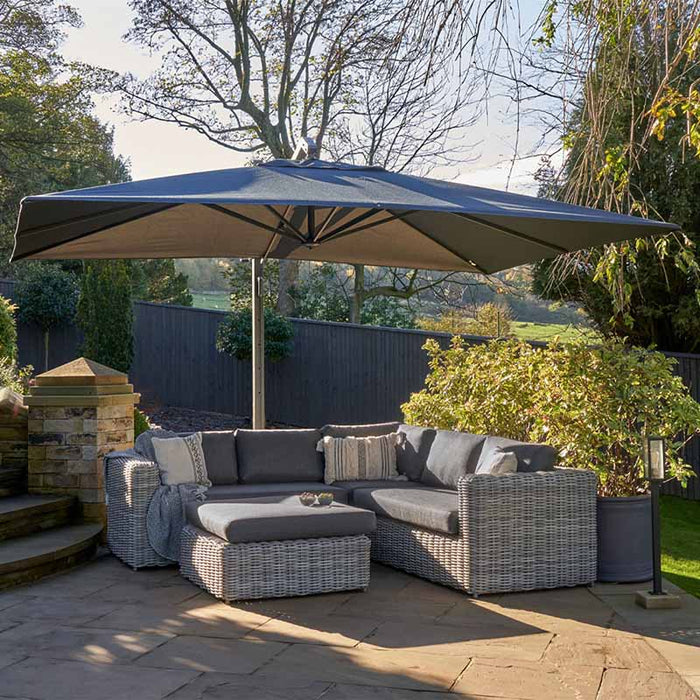 Tuscany Outdoor Corner Seating Set in a garden under a parasol.