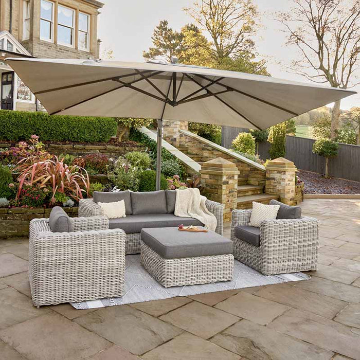 Tuscany Outdoor Seating Set in a garden setting with cool grey rattan and plush anthracite cushions under a parasol.