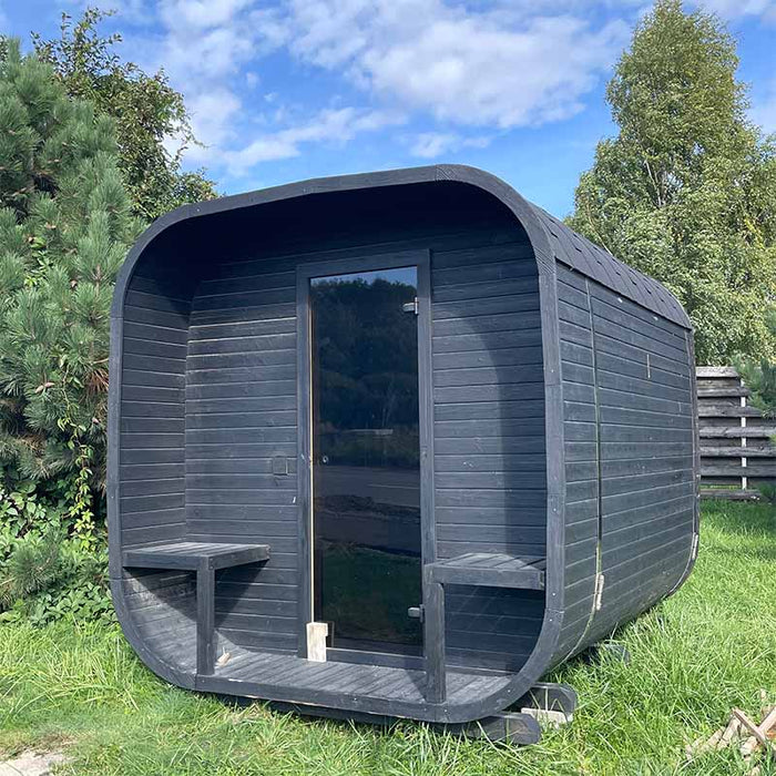 Ula Classic 6-person outdoor sauna in sleek charcoal black finish with integrated front benches, set up in a garden for a contemporary spa experience.