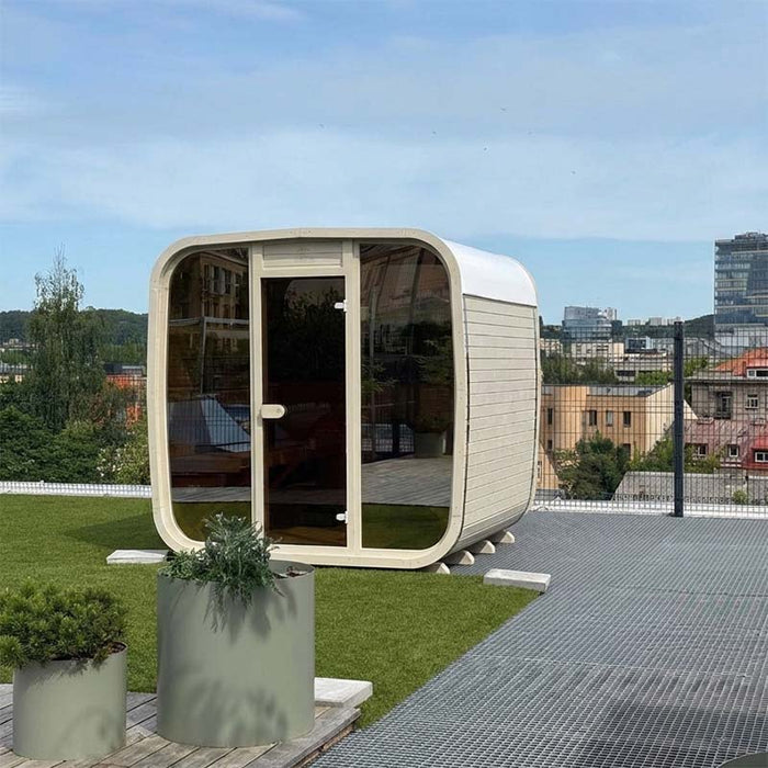 Side angle of the Ula Classic 6-person outdoor sauna in whitewashed finish on a rooftop garden, showcasing its modern design and serene placement.
