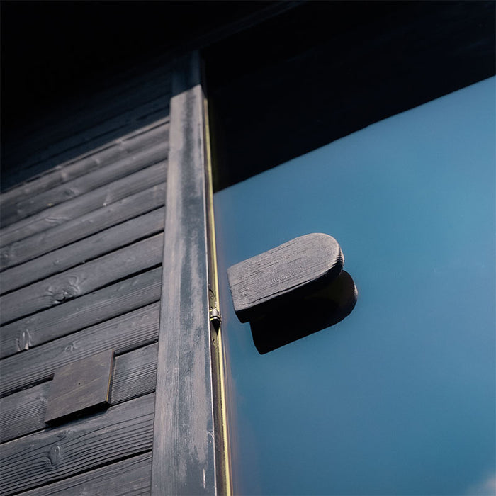 Close-up of the Ula Grand 6-Person Outdoor Sauna in Ebony finish showing the glass door and handle.