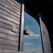 Close-up of the Ula Grand 6-Person Outdoor Sauna in Ebony finish with reflective glass door under a blue sky