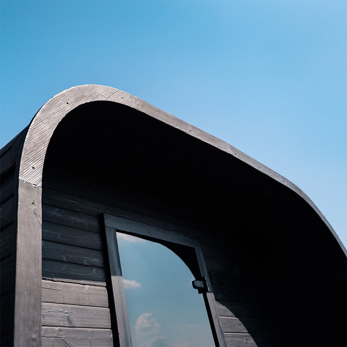 Side view of the Ula Grand 6-Person Outdoor Sauna in Ebony finish showing the curved roof and timber exterior.