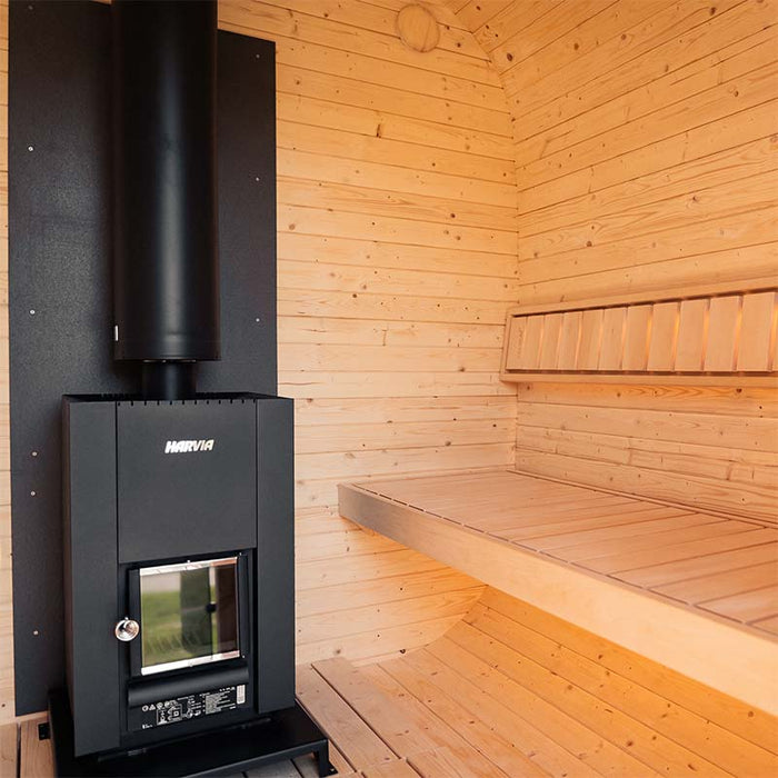 Interior of the Ula Grand 6-person outdoor sauna with Harvia wood-burning heater and wooden bench seating.