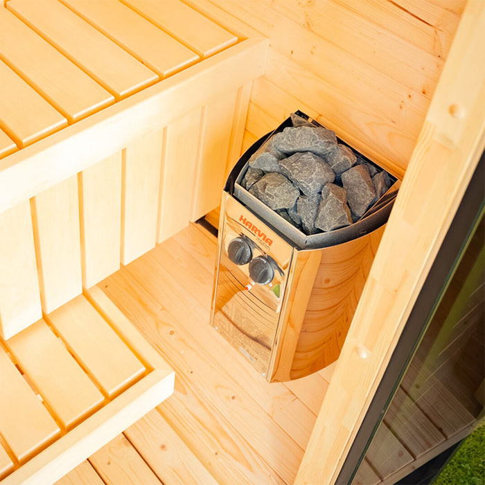 Close-up of the Ula Micro 2-person outdoor sauna interior, showing the smooth timber bench seating and Harvia heater with sauna stones for an authentic wellness experience.