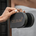Close-up of a hand opening the Ula Mini sauna door with CELSIUM-branded handle detail.