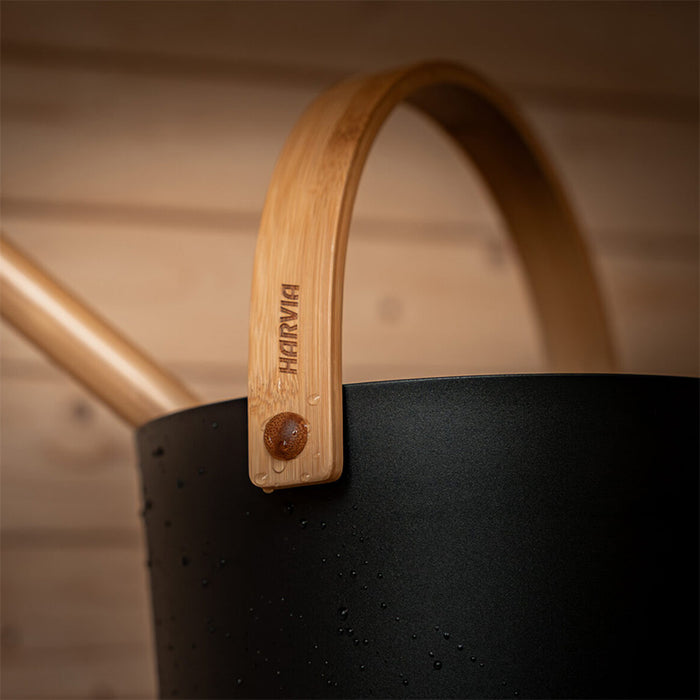 Close-up of a Harvia sauna bucket and ladle with bamboo handle, placed inside the Ula Mini sauna.