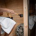 Man enjoying the Ula Mini 2-person outdoor sauna while pouring water onto hot stones for steam.