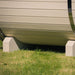 Close-up of the base support structure of a white Ula Mini sauna, resting on green grass.