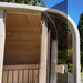 Close-up view of the white Ula Mini 2-person outdoor sauna with an open glass door and light wood interior.