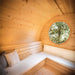 Interior view of Delight Outdoor Sauna showing benches with pillows and round window.