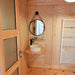 Close-up of the bathroom in the Glamping Cube 51m² U-Shape, highlighting the wooden interiors and round mirror detail.