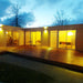 Front evening view of the Glamping Cube 51m² U-Shape with glass panels reflecting soft yellow light.