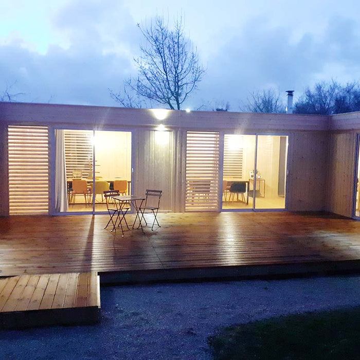 Side perspective of the Glamping Cube 51m² U-Shape featuring wooden decking and ambient lighting.