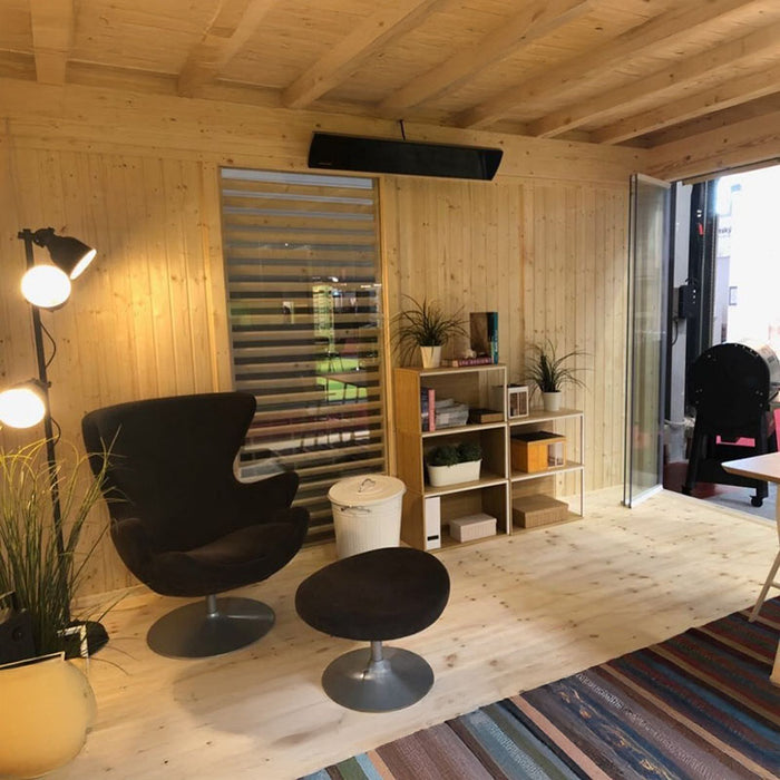 Interior of the Insulated Garden Office Cube 3 x 4m featuring a comfortable reading nook, shelf space, and modern lighting, creating a warm and inviting atmosphere.