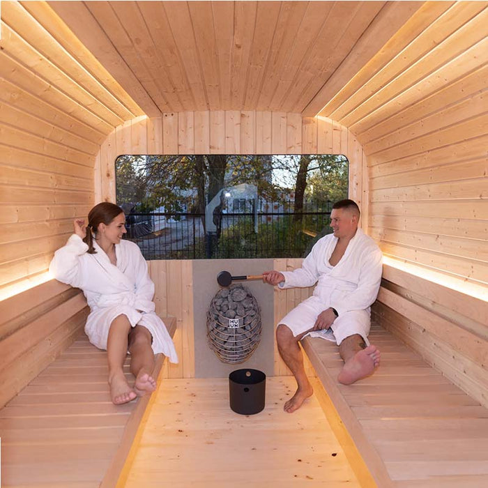 Couple in Luna Outdoor Sauna with man using the ladle.