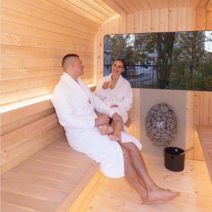 Smiling couple enjoying the Luna Outdoor Sauna 2.3 x 2.4m with drinks.