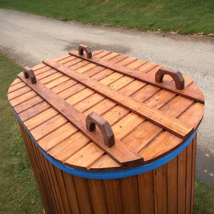 Fiberglass Ofuro Hot Tub with a wooden cover, featuring handles, on a grassy path.