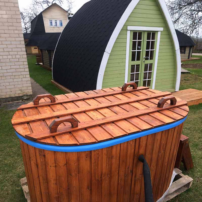 Fiberglass Ofuro Hot Tub with a wooden cover, next to a green cabin.