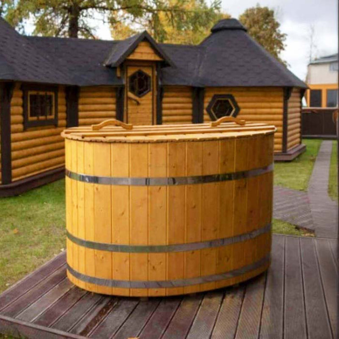 Oval cold tub placed outside a log cabin.