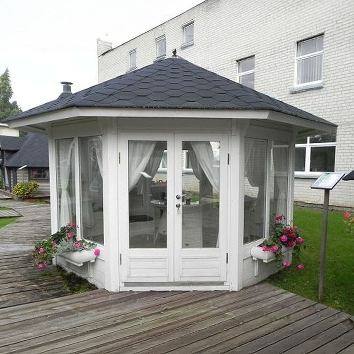 White Pavilion 10m² Sun with octagonal design, large double-glazed windows, black roof shingles, and vibrant flower pots set in a garden setting.