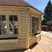 Close-up of the Pavilion 14.9m² exterior, featuring natural wood walls, large double-glazed windows, and a red shingle roof.