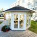 Pavilion with Large Windows 10m² installed outdoors, showcasing its octagonal design, black shingle roof, and seamless integration into a landscaped garden.