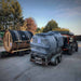 Two traditonal sauna barrels wrapped in plastic being transported on trailers.