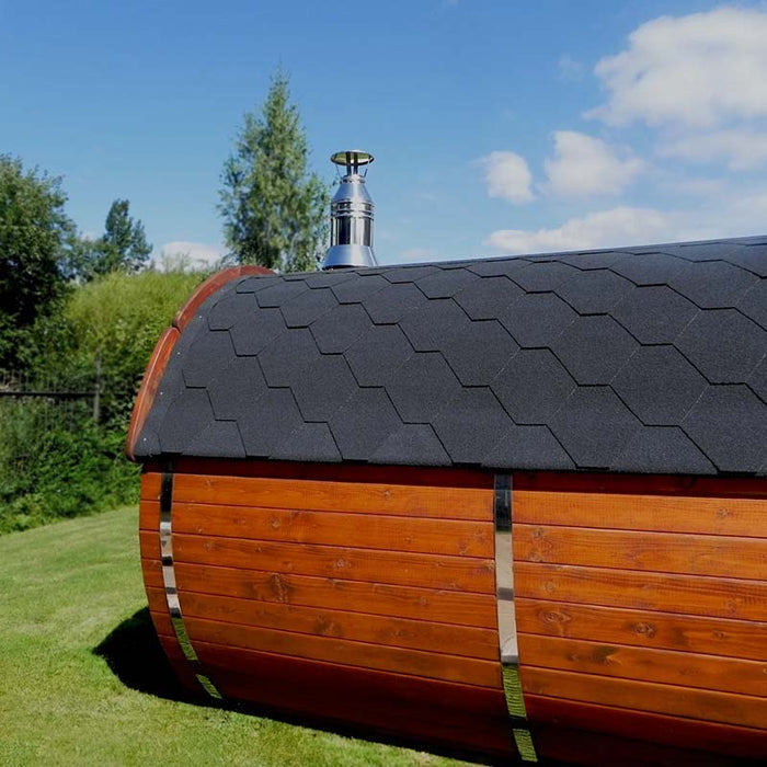 Close-up of a traditional barrel sauna with a black shingle roof and chimney.