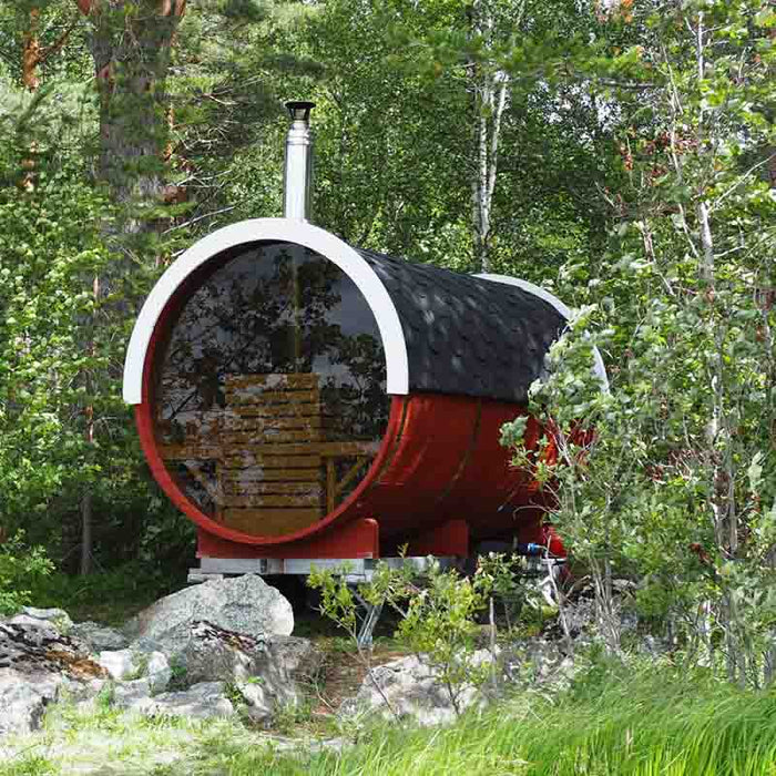 Traditional Sauna Barrel 1.9 x 3m, an outdoor sauna with a cylindrical shape, black shingled roof, and glass front door, surrounded by greenery.