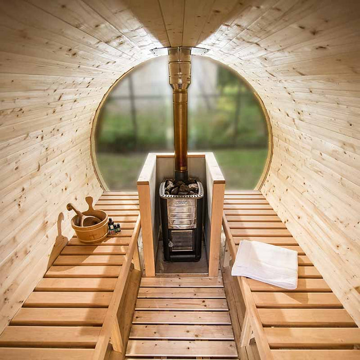 Interior of a Traditional Sauna Barrel 1.9 x 3m, featuring wooden benches and a central wood-burning sauna stove with stones and sauna accessories.