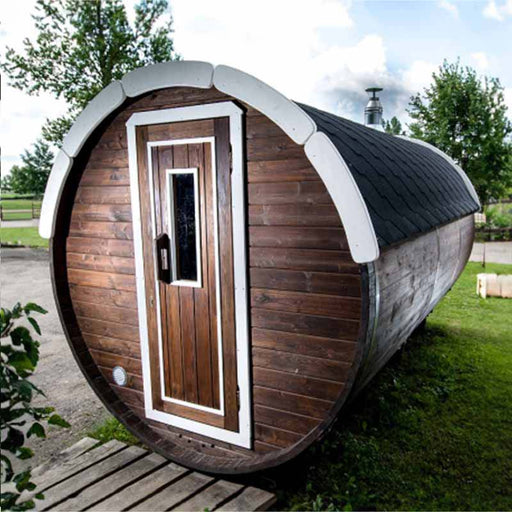 A Traditional Sauna Barrel 2.2 x 4m sauna with a front door featuring a rectangular window, curved roof and white trim around the edges.