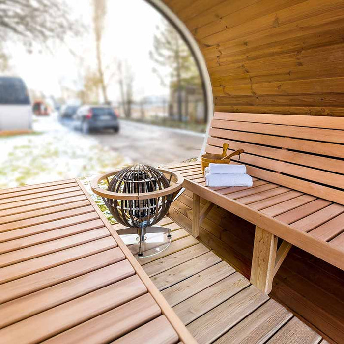 Diagonal interior view of Sauna Barrel from Thermowood displaying harvia heater, bucket and towel.