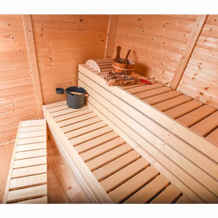 Interior view of wooden sauna benches with headrest, bucket and ladle.