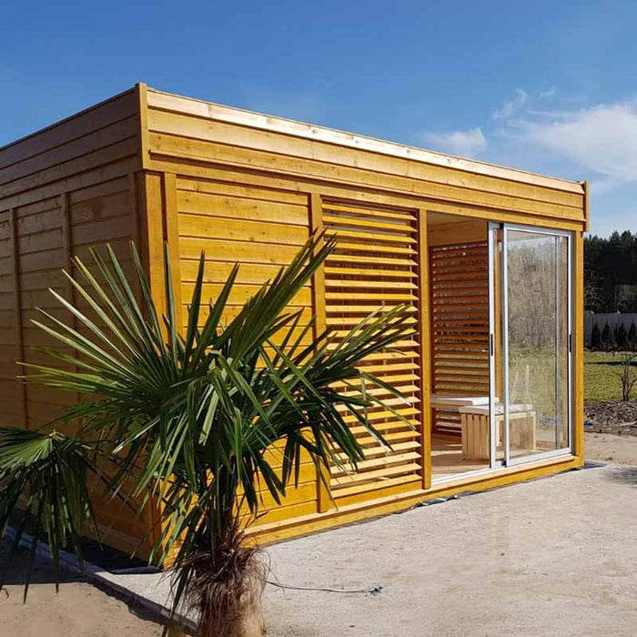 Side angle of the Traditional Sauna Cube 3 x 4m in garden setting with plant.