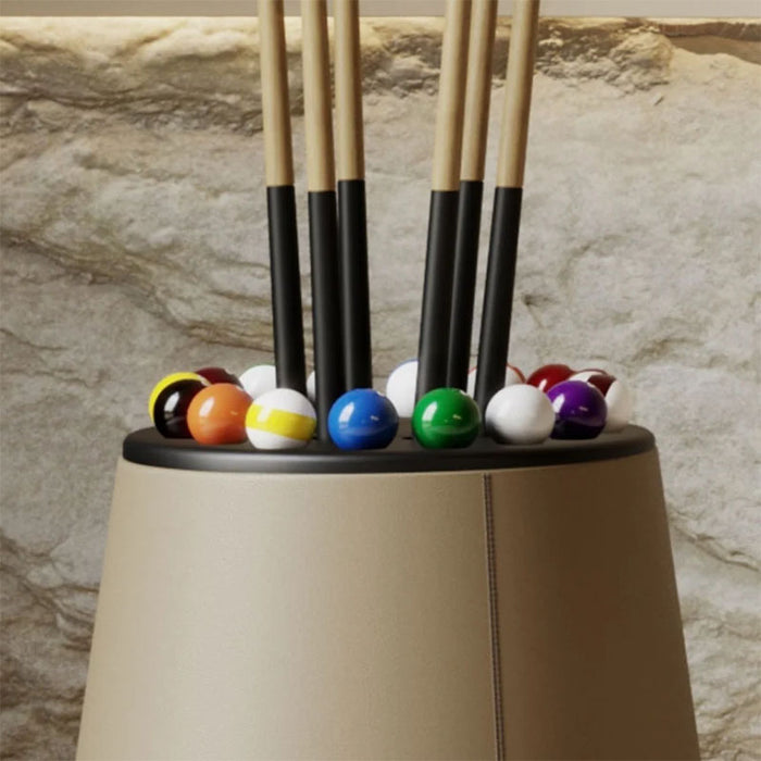 Close-up of the Vismara Bobo Cue Rack showcasing pool cues and vibrant billiard balls in an elegant matte beige finish against a stone wall.