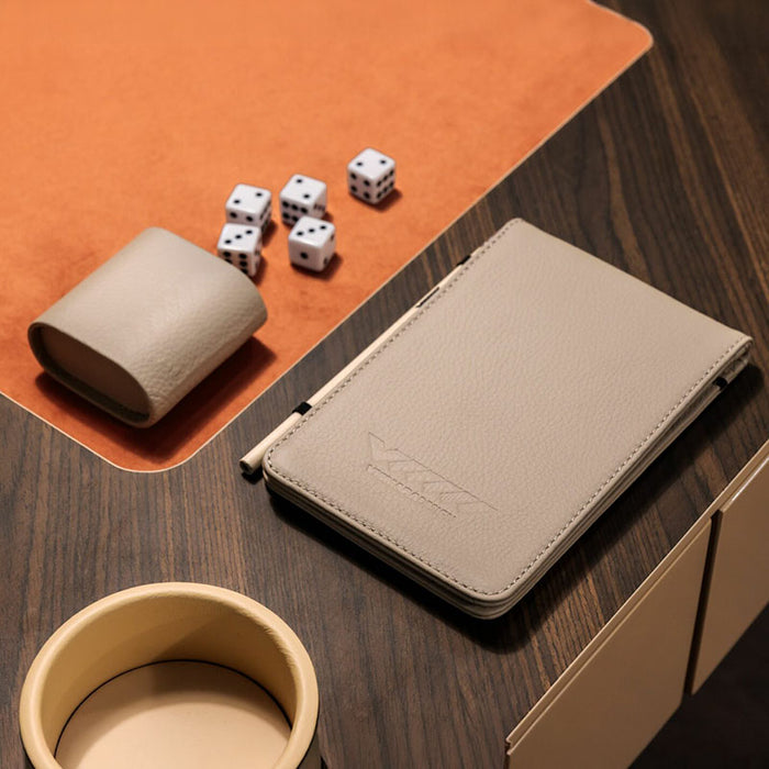 Close-up of Vismara Enigma game table with leather accessories, dice, and pen tray on a rich wood and suede surface – luxury tabletop gaming essentials.