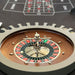 Detailed view of the roulette wheel on Vismara Montecarlo Table with chrome spinner and wooden inlay, black felt betting area in the background – luxury casino elegance.