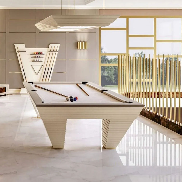 The cream-coloured Vismara Newde Pool Table elegantly positioned in a sunny room, complete with a matching cue rack and stylish accents.