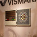 Vismara Nido Dartboard Cabinet displayed open on a blush pink wall, featuring precision-designed dartboard, rich wood backing, and neatly arranged multicoloured darts.