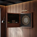 Vismara Nido Dartboard Cabinet in brown finish, opened in a wood-panelled game room, showing elegant interior with full dart set and atmospheric lighting.