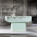 Mint-green Oskar Foosball Table displayed in a contemporary showroom, surrounded by metallic chain accents.