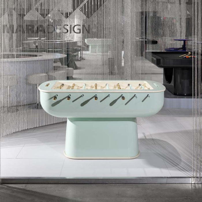 Mint-green Oskar Foosball Table in a contemporary showroom, surrounded by metallic chain decor.