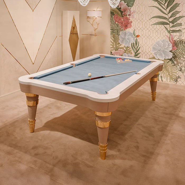 The Vismara Regis Pool Table styled with a blue Simonis cloth and gold-plated accents, set against a luxurious floral backdrop.