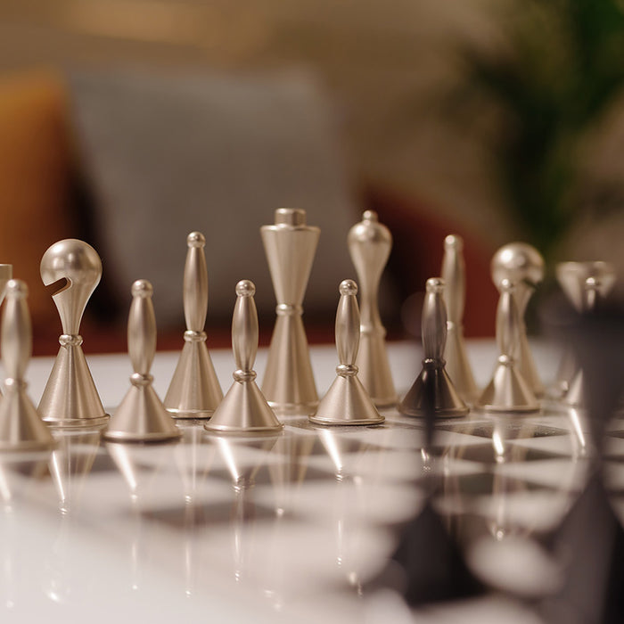 Close-up view of Vismara Scaccomatto Chess Set featuring sculptural metal chess pieces with a modern, artistic design on a high-gloss playing board.